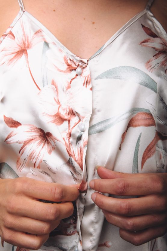 Close up van vrouw die haar satijnen pyjama dicht knoopt