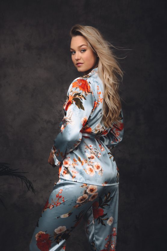 Vrouw in satijnen pyjama met bloemendesign van de achterkant