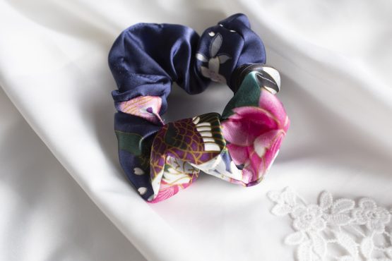 Satijnen scrunchie blauw met bloemen liggend op witte kimono satijn