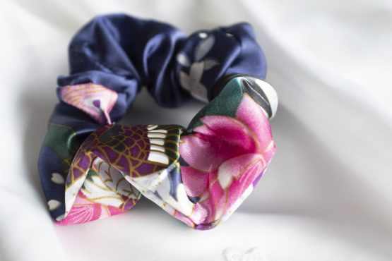 Satijnen scrunchie blauw met bloemen liggend op witte kimono satijn