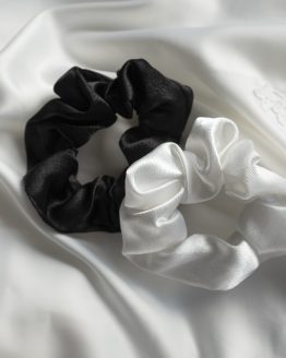 satijnen scrunchie zwart en wit liggend op witte kimono satijn