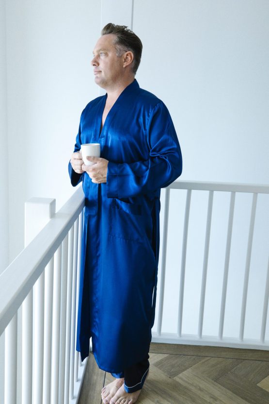 man in blauwe satijnen kimono met kop koffie