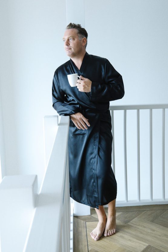 Man in zwarte satijnen kimono met kop koffie