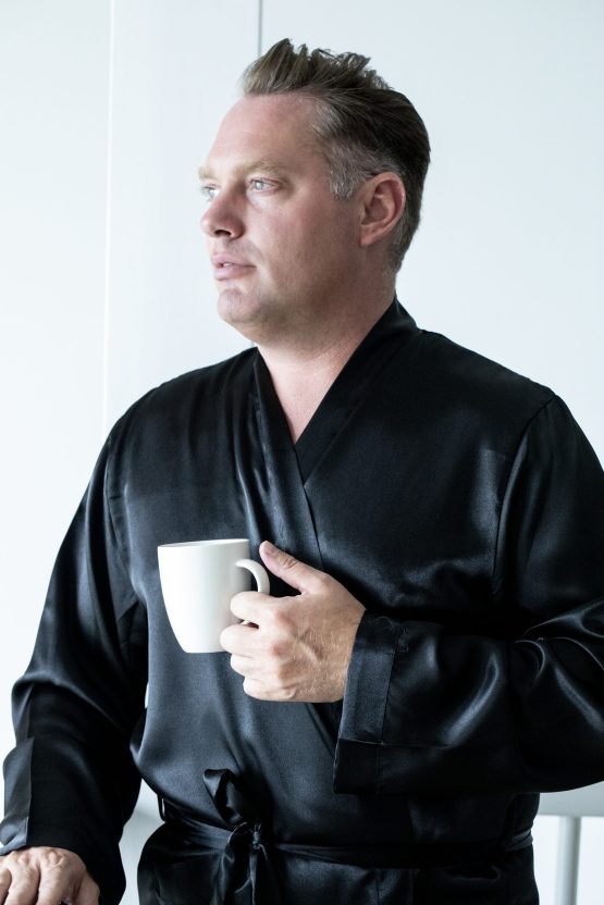 Man in zwarte satijnen kimono met kop koffie