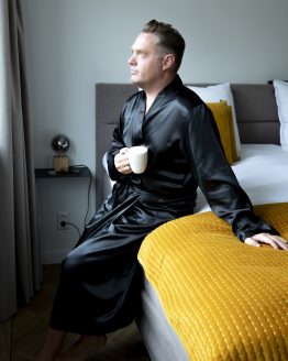 Man in satijnen kimono op bed met kop koffie