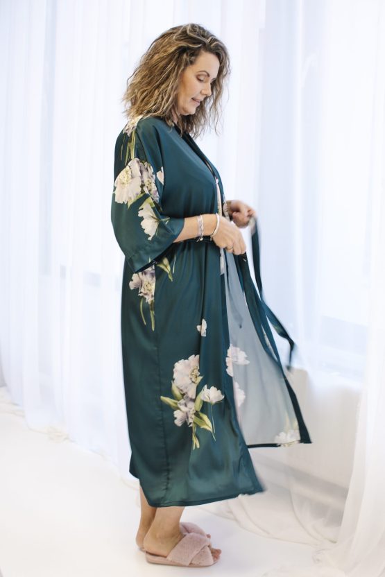 Vrouw in groene satijnen kimono bij gordijn