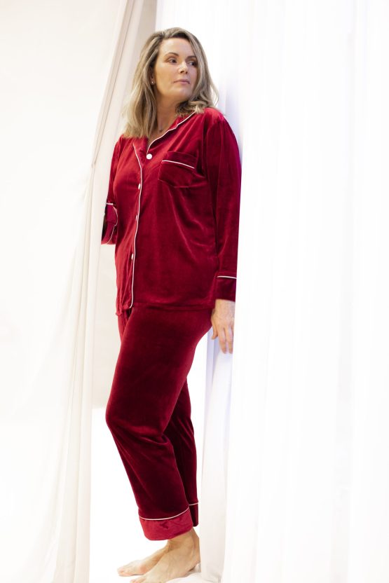 vrouw in rode fluwelen pyjama uit het raam kijkend