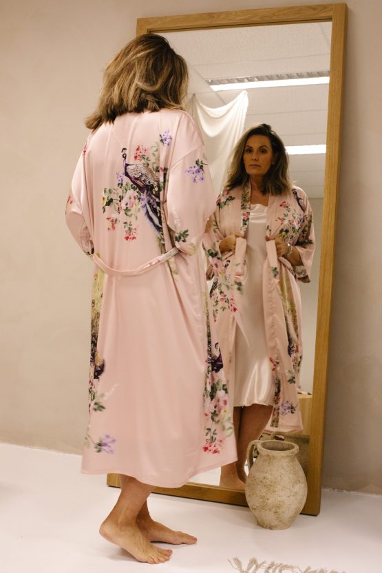 Vrouw in satijnen kimono roze met pauw voor spiegel