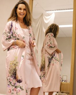 Vrouw in satijnen roze kimono met pauw voor de speigel